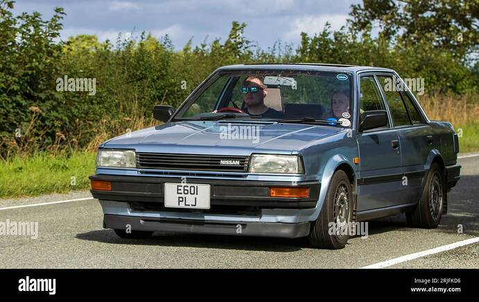 woburn-beds-uk-19-de-agosto-2023-1988-azul-nissan-bluebird-coche-clasico-que-viaja-en-una-carretera-de-campo-ingles-2rjfkd6